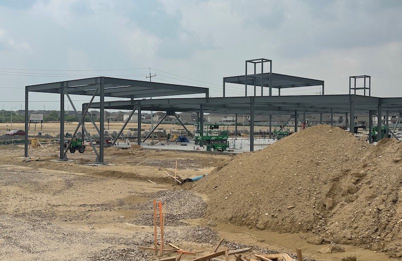 Metal frame of the new ER Wright Ranch building with large pile of dirt in front