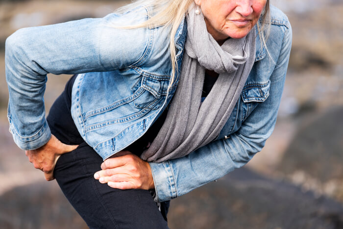 Mature woman on outdoor walk experiencing hip pain.