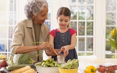 A woman making a salad with her granddaughter